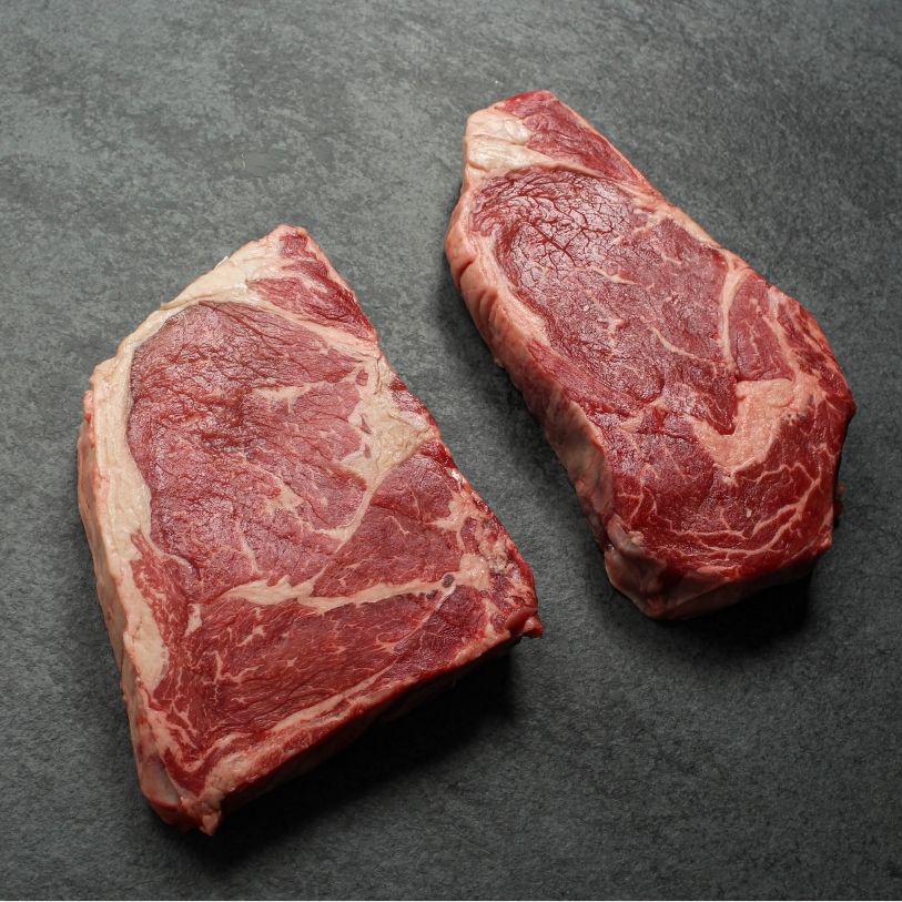 angled view of two raw rib eye steaks