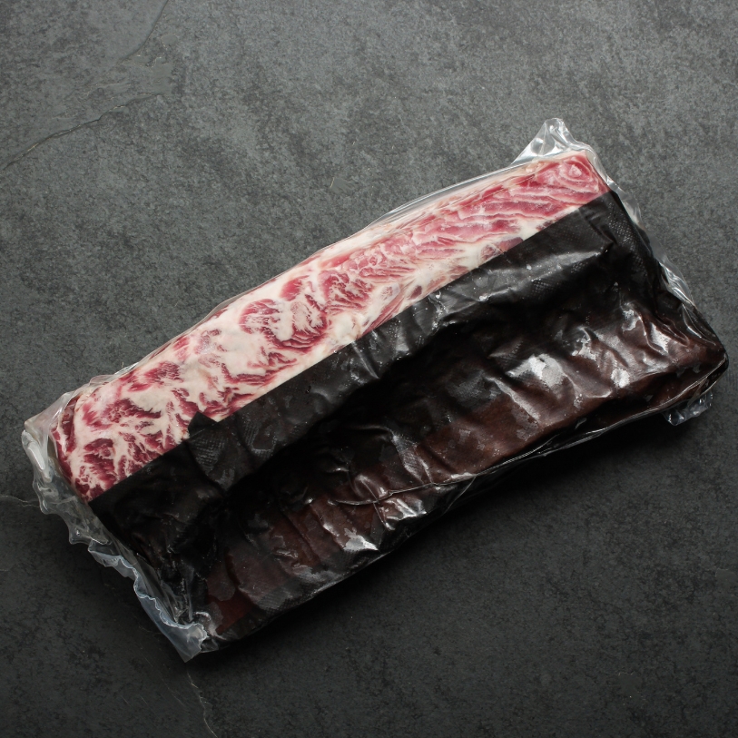 Overhead view of a whole Spanish Iberico Pork Rack in vacuum packaging.