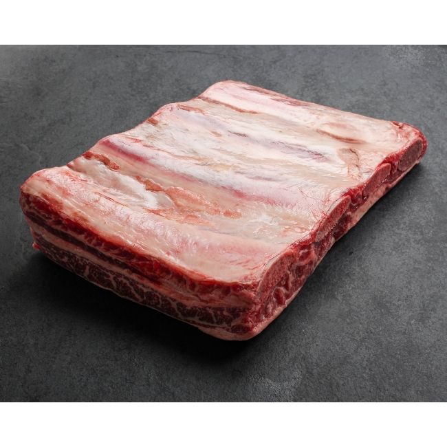 angled view of a piece of raw beef short ribs with 4 bones