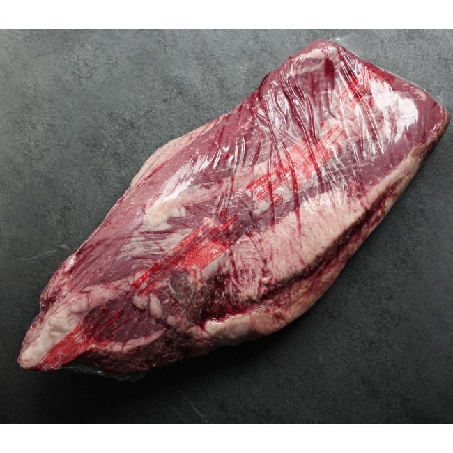 overhead image of the fatty side of a raw beef brisket in vacuum packaging