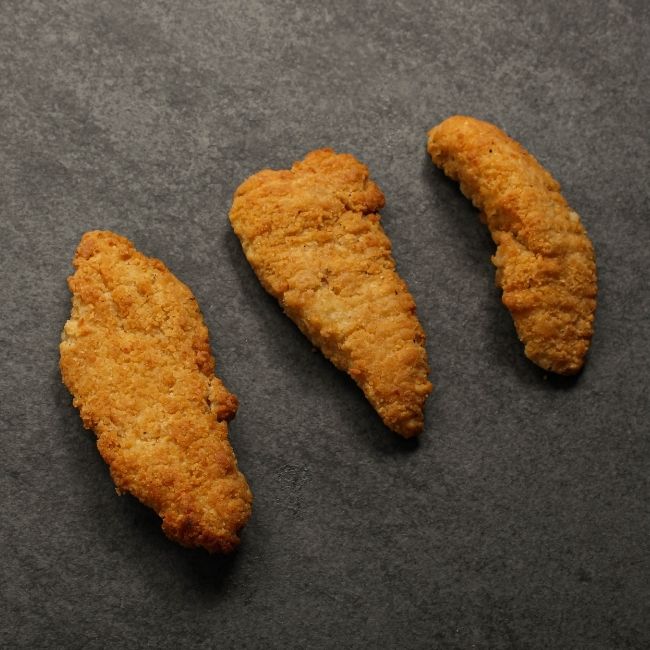 angled view of cooked golden-brown, crispy chicken fingers