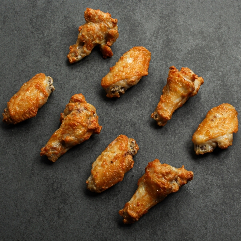 Angled overhead image of eight, prepared fully cooked chicken wings