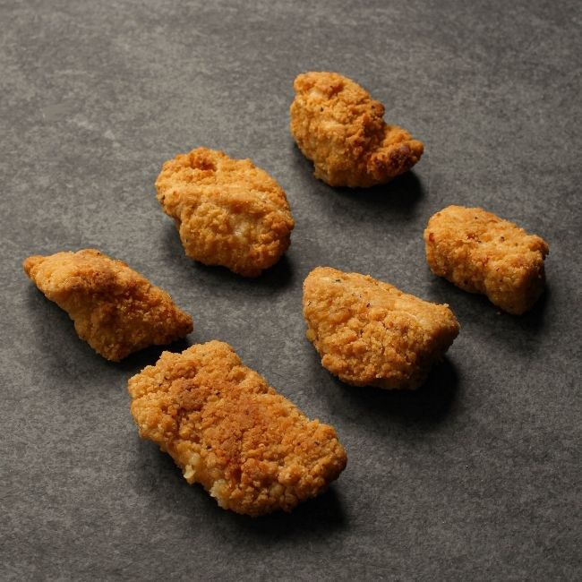 angled view of cooked, golden-brown crispy breaded chicken bites