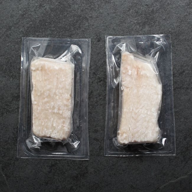 overhead view of two pieces of raw haddock filets in vacuum packages