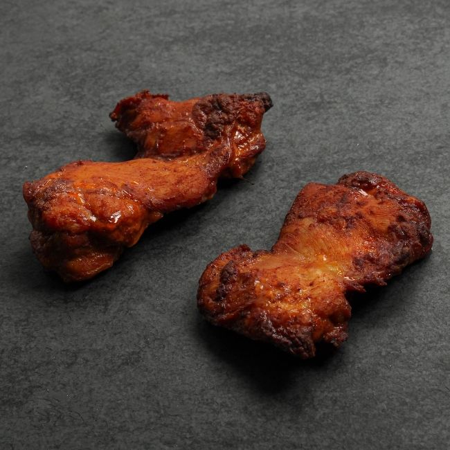 angled view of two cooked boneless skinless chicken thighs coated in a sweet bbq glaze
