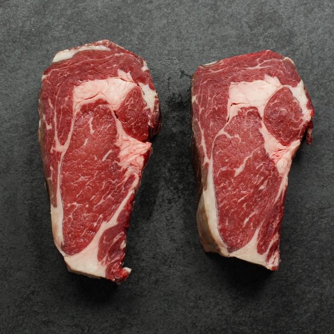 overhead view of two raw dry aged rib eye steaks