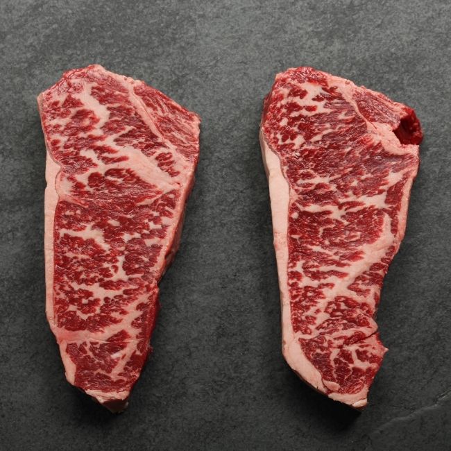 overhead image of two heavily marbled Australian wagyu new york steaks