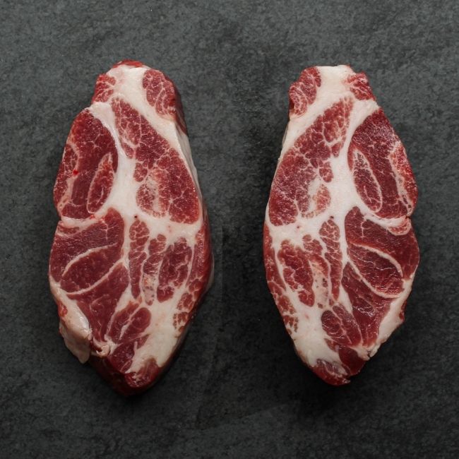 overhead view of two heavily marbled iberico pork collar steaks