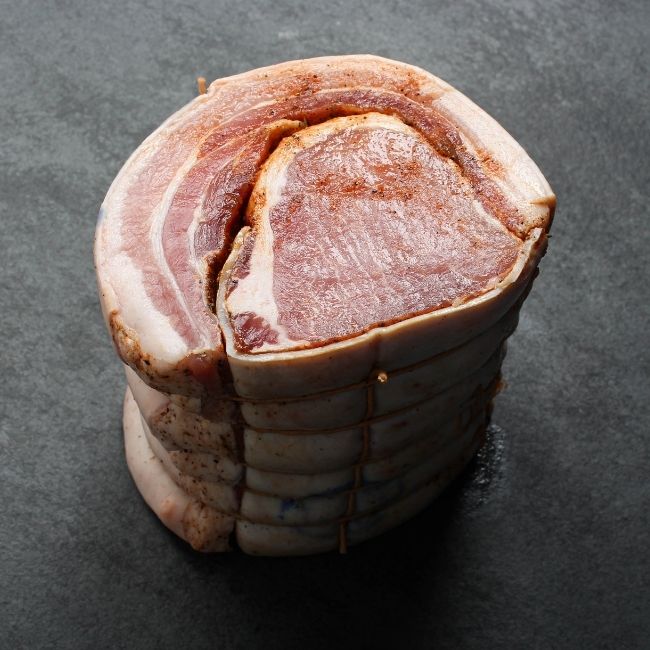 angled view of a raw, seasoned and tied porchetta roast