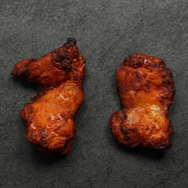 overhead view of two cooked boneless skinless chicken thighs coated in a sweet bbq glaze