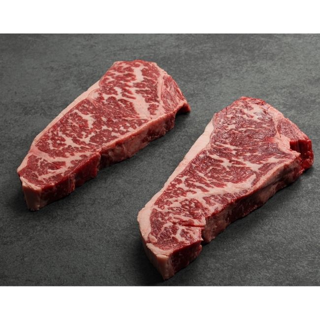 angled view of two heavily marbled Australian wagyu new york steaks